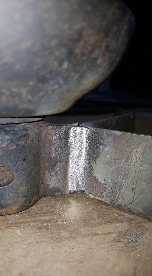 Close-up of a clean finished weld on a heavy equipment bracket